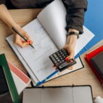 Accountant analyzing financial documents with a calculator on a desk, highlighting business tasks.