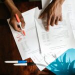 Overhead view of hands highlighting financial documents on a desk.