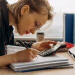 Young woman diligently working on accounting with a calculator and documents. Perfect for business and finance themes.