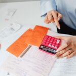 Businesswoman calculates expenses using receipts and calculator at desk. Ideal for finance, accounting themes.